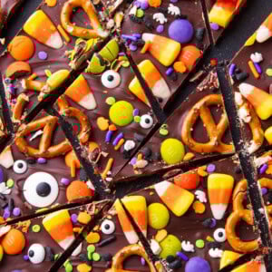 Halloween bark broken into pieces on a serving board topped with Halloween candy and sprinkles