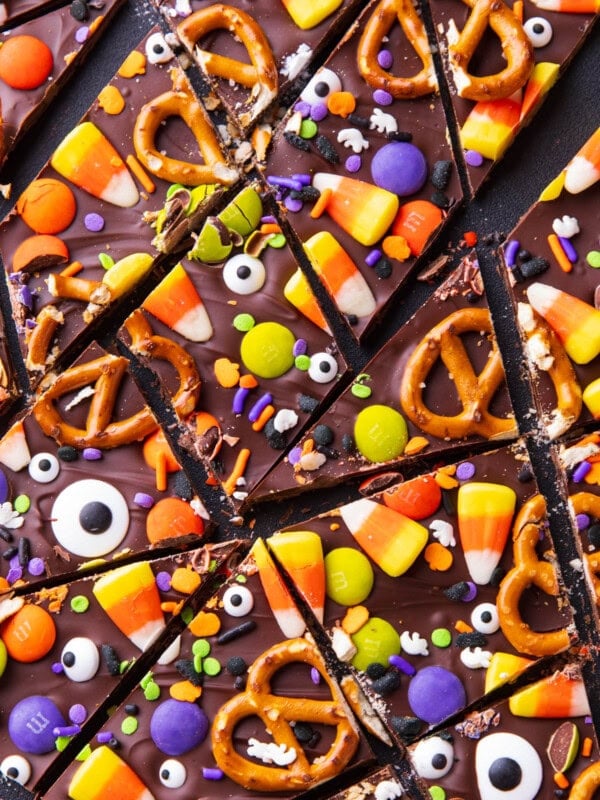 Halloween bark broken into pieces on a serving board topped with Halloween candy and sprinkles