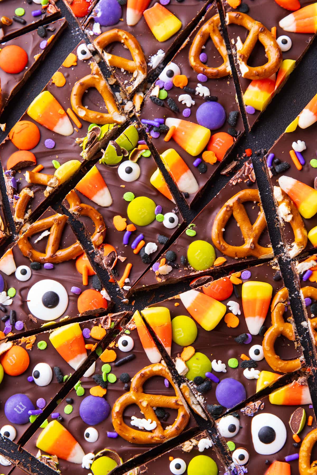 Halloween bark broken into pieces on a serving board topped with Halloween candy and sprinkles