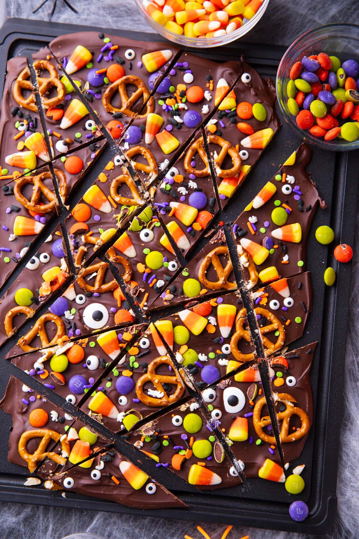 Halloween chocolate bark on a Halloween party table with spiderwebs, candy, and spooky spiders