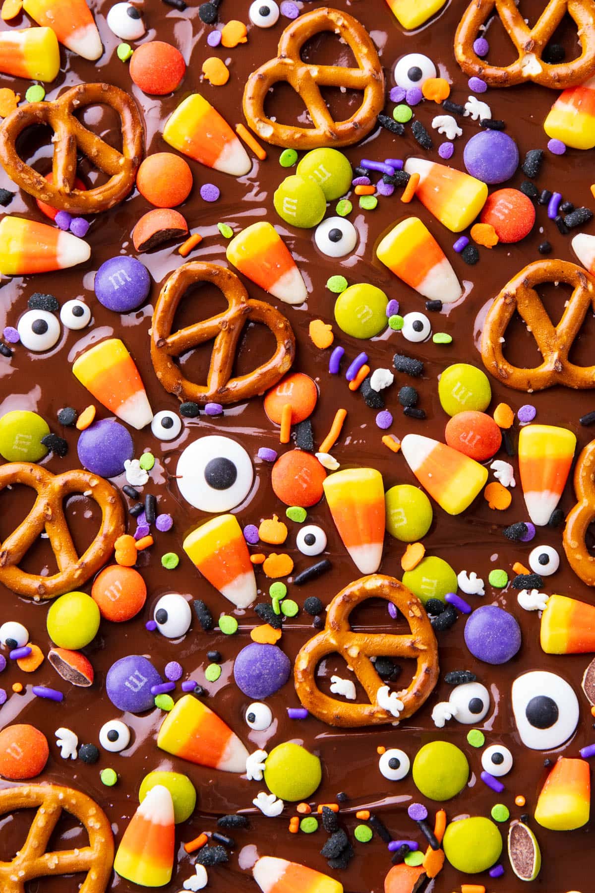 Melted chocolate spread on a baking sheet with Halloween bark toppings pressed in