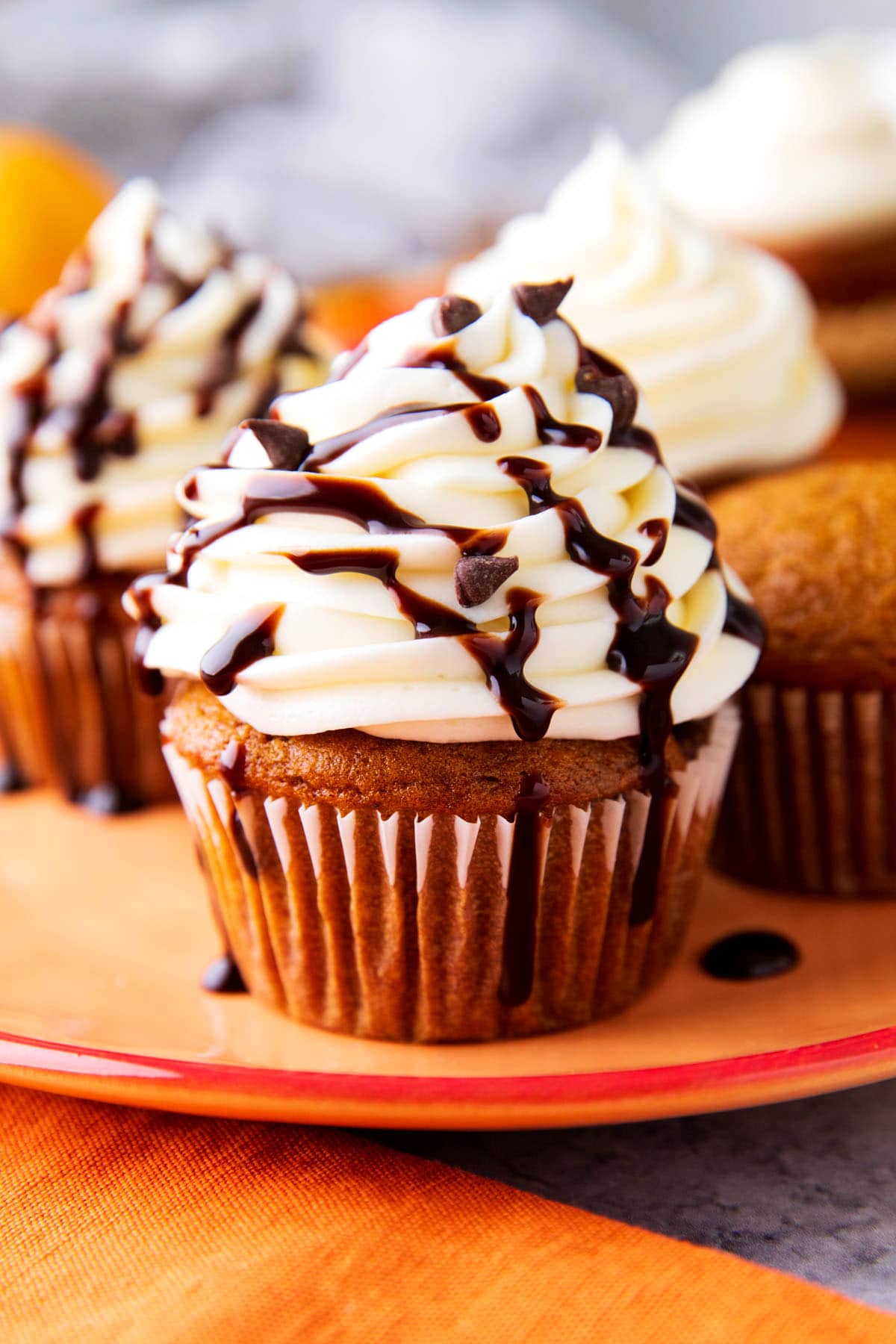 Pumpkin chocolate chip cupcakes are moist and topped with cream cheese frosting with chocolate chips and chocolate drizzle.