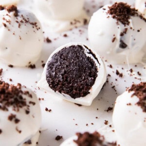 This Oreo Balls recipe is easy, sliced in half to show the cake ball center packed with Oreo cookies on a sheet with more Oreo cream cheese truffles