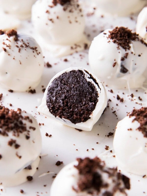 This Oreo Balls recipe is easy, sliced in half to show the cake ball center packed with Oreo cookies on a sheet with more Oreo cream cheese truffles