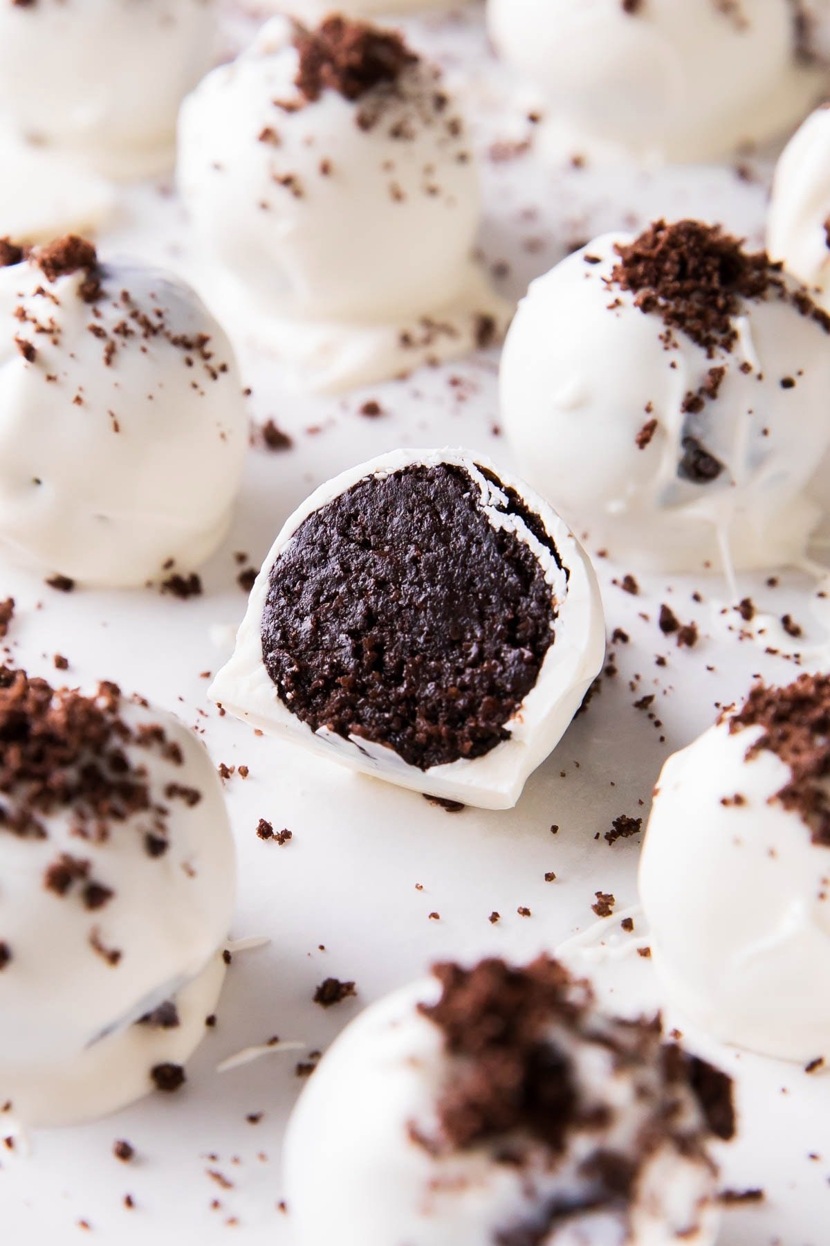 This Oreo Balls recipe is easy, sliced in half to show the cake ball center packed with Oreo cookies on a sheet with more Oreo cream cheese truffles.