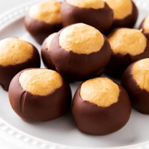 Close up of Buckeye Balls to show creamy peanut butter texture wrapped in chocolate arranged on a plate for the best recipe for buckeyes