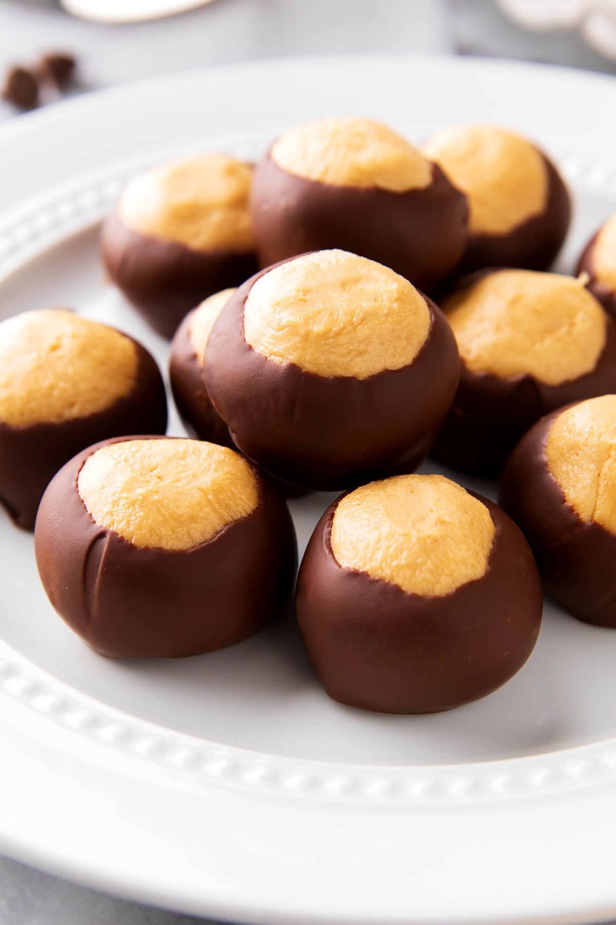 Close up of Buckeye Balls to show creamy peanut butter texture wrapped in chocolate arranged on a plate for the best recipe for buckeyes.
