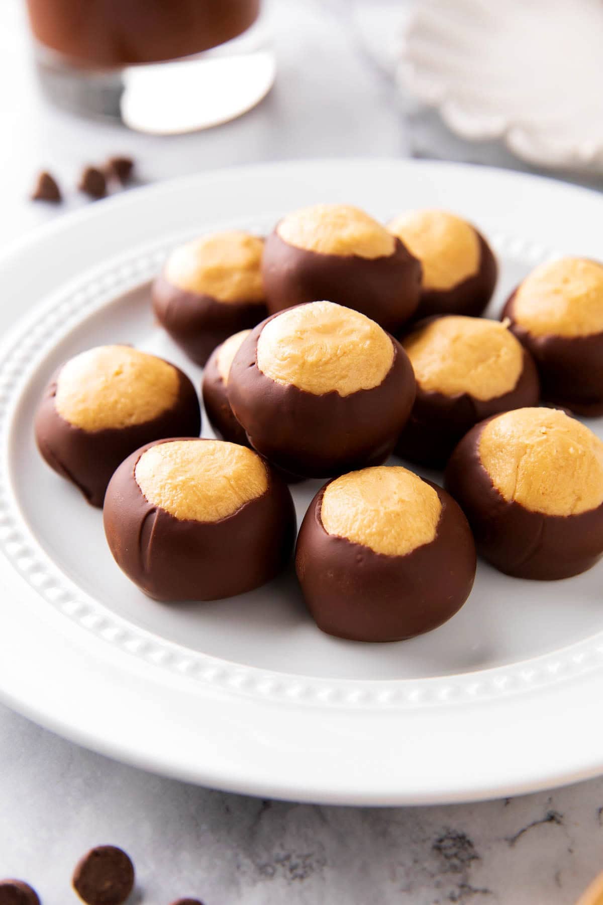 This buckeye ball recipe features peanut butter balls wrapped in rich chocolate served on a plate as an easy homemade candy recipe.