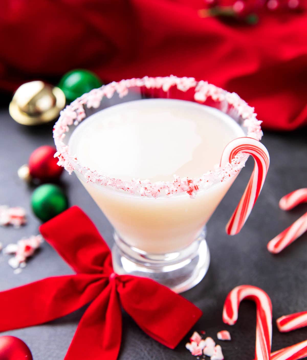 Candy Cane martini is a festive Christmas cocktail served in a crushed candy cane rim cocktail glass with red ribbons.