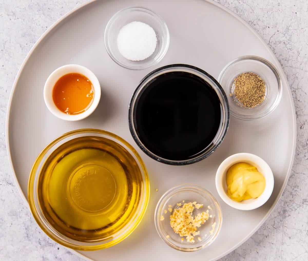 Homemade balsamic salad dressing ingredients including balsamic vinegar, olive oil, honey, dijon mustard, salt and pepper.