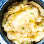 Quick and easy creamy mashed potatoes are served in a bowl topped with melted butter, chives, salt and pepper