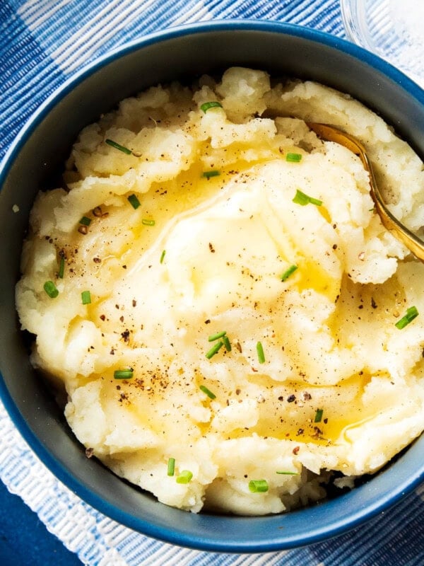Quick and easy creamy mashed potatoes are served in a bowl topped with melted butter, chives, salt and pepper
