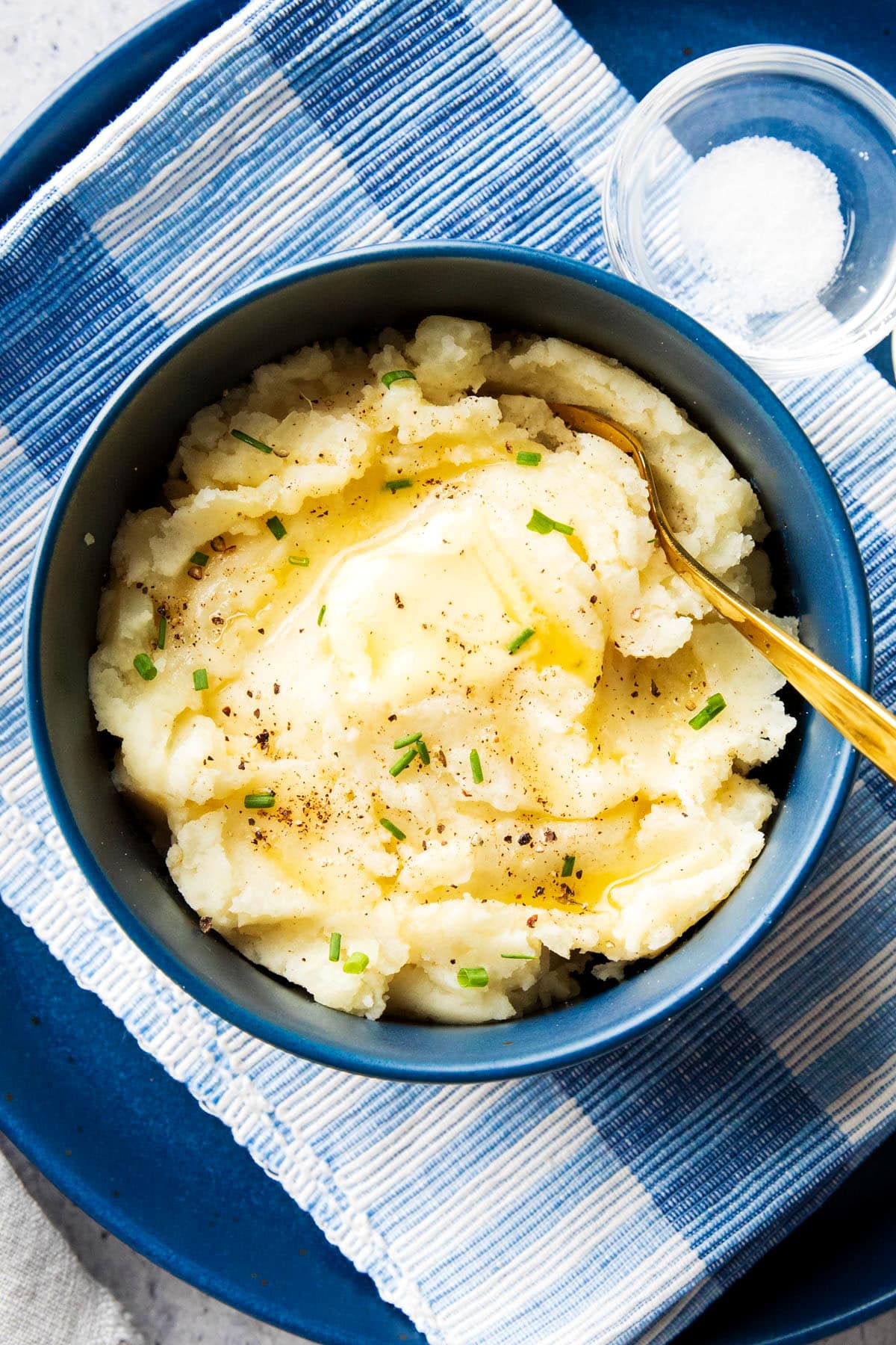 Homemade mashed potatoes have a smooth texture that's buttery with tasty bits of potatoes topped with chives, salt, and pepper.