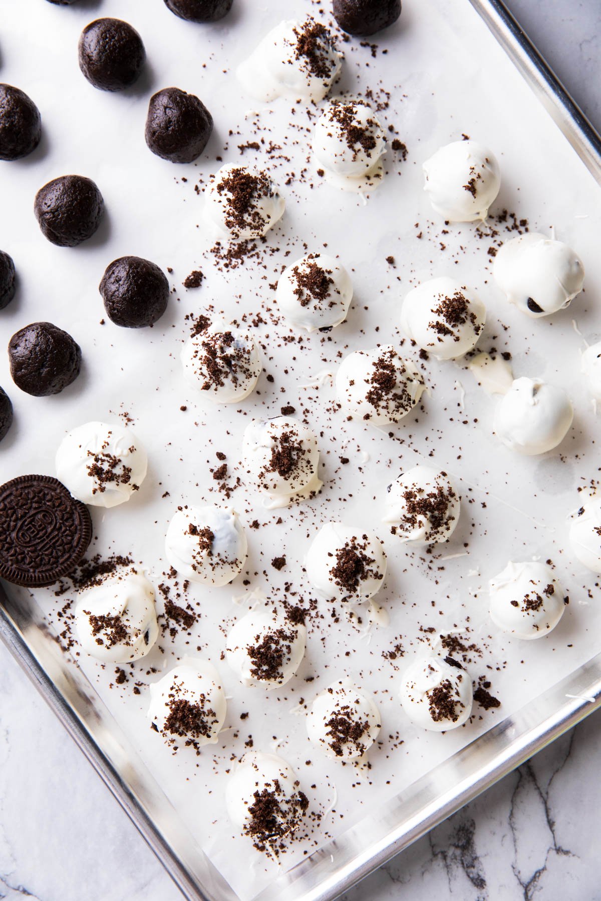 A photo showing how to make the best Oreo balls - rolling Oreo balls in white chocolate to coat.