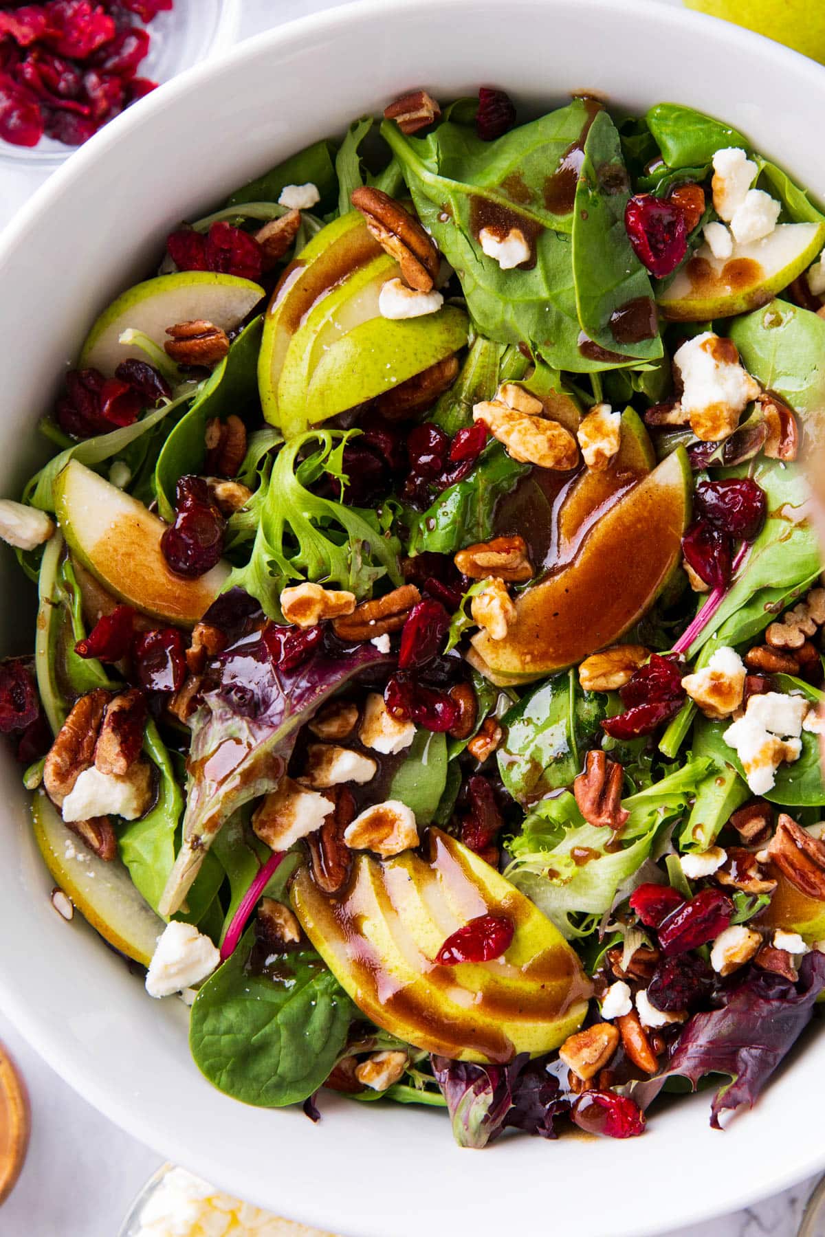 Pear Salad with balsamic dressing drizzled over lettuce, pears, cranberries, pecans, and feta cheese.
