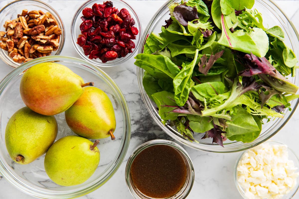 Pear Salad ingredients include pears, spring mix lettuce, dried cranberries, feta cheese, gorgonzola cheese or goat cheese, pecans, and balsamic vinegar.