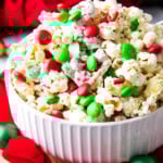This delicious Christmas Popcorn Recipe served in a festive bowl packed with salty popcorn, pretzels, red and green M&M's and drizzled with white chocolate