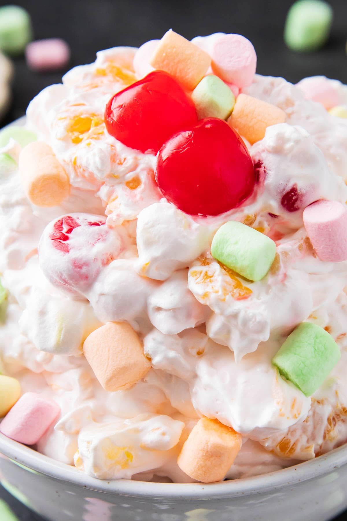 Close up of Ambrosia fruit salad to show sweet fruit salad dessert-like texture with sweet coconut, marshmallows, mandarin oranges, cherries, and pineapple.