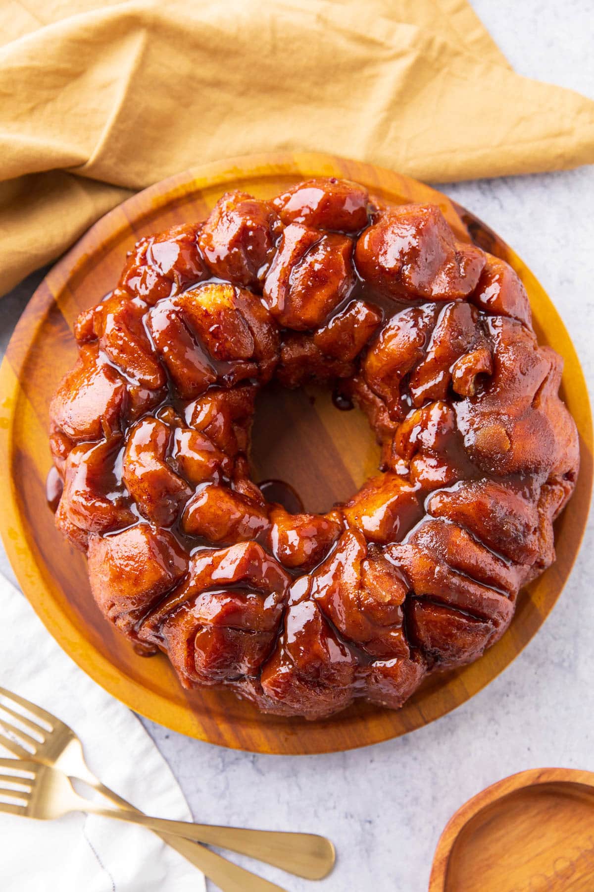 Overhead Monkey Bread w yellow cloth - Easy cinnamon roll monkey bread is made with refrigerated Pillsbury cinnamon roll dough, cinnamon sugar, brown sugar glaze, and coated in icing.