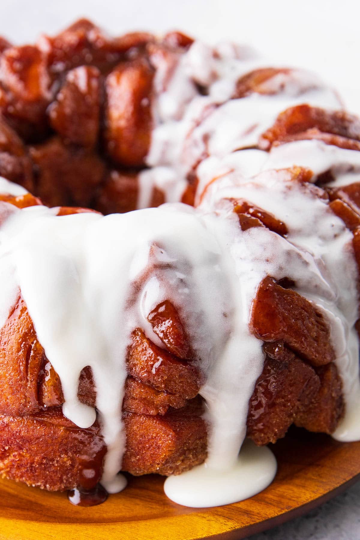 Cinnamon roll icing drips off of cinnamon roll monkey bread served on a breakfast platter.