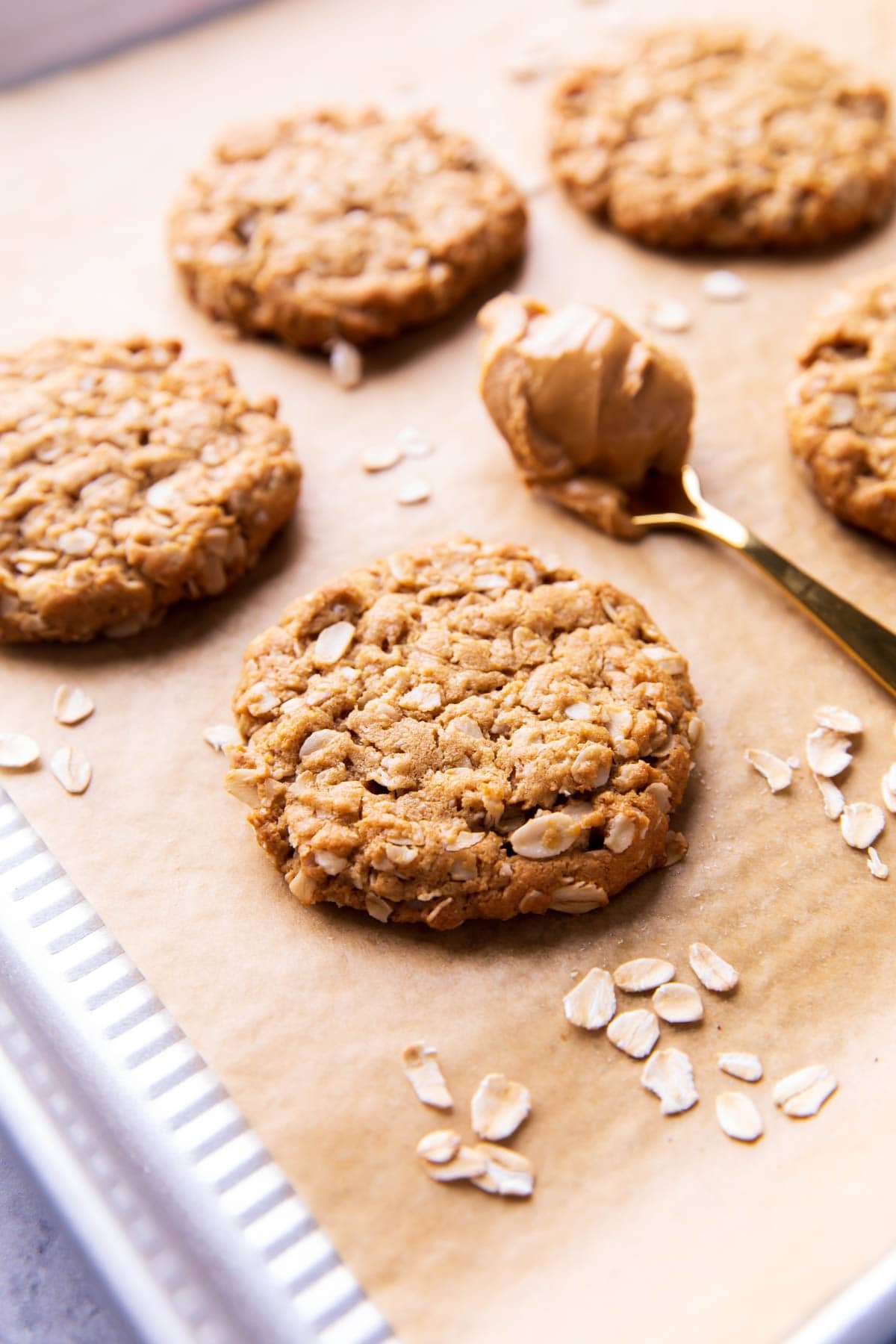 Easy peanut butter oatmeal cookies are fresh-baked on a parchment-lined sheet with oats.