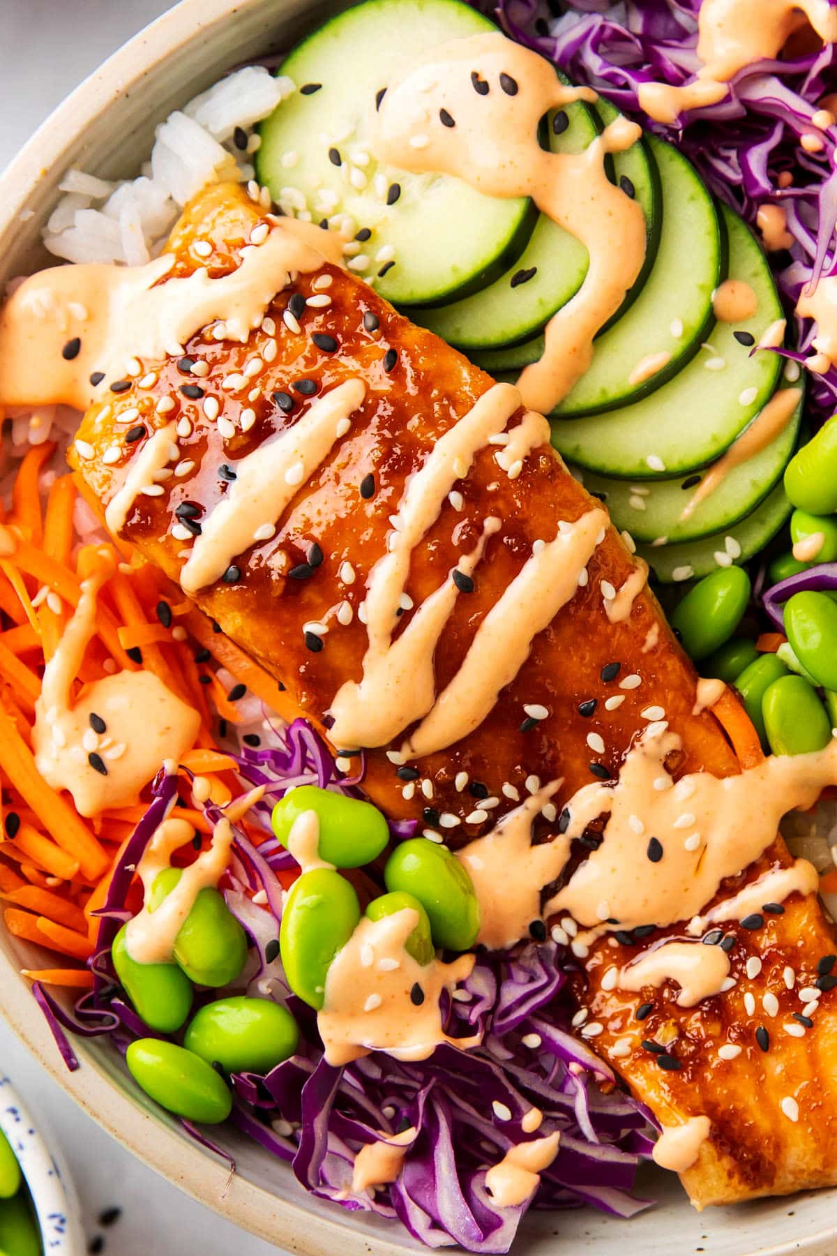 Close up of sriracha mayo drizzled over soy sauce salmon served in this avocado salmon rice bowl.