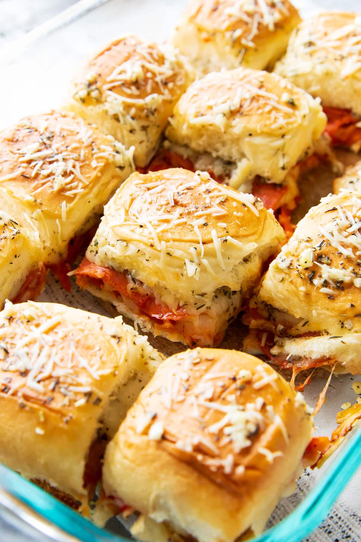 This recipe for pizza sliders in a casserole dish with soft Hawaiian rolls, marinara sauce, cheese, and pizza toppings are ready to serve as appetizers.