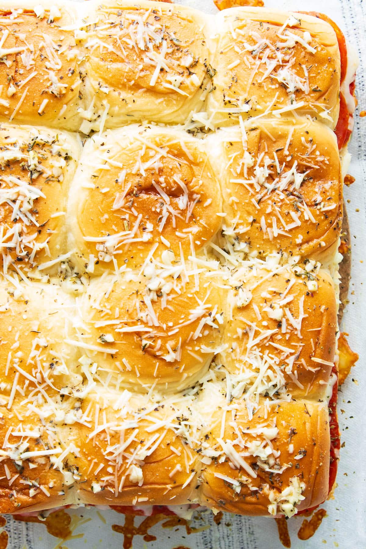 Golden brown Pizza sliders recipe - Hawaiian rolls are topped with buttery garlic, cheese, and Italian seasoning.