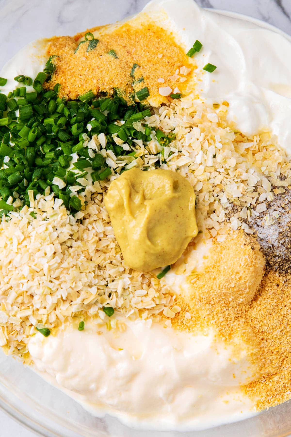 Close up of sour cream and onion dip ingredients - chives, onion powder, garlic powder, Dijon mustard and more make this creamy appetizer dip.