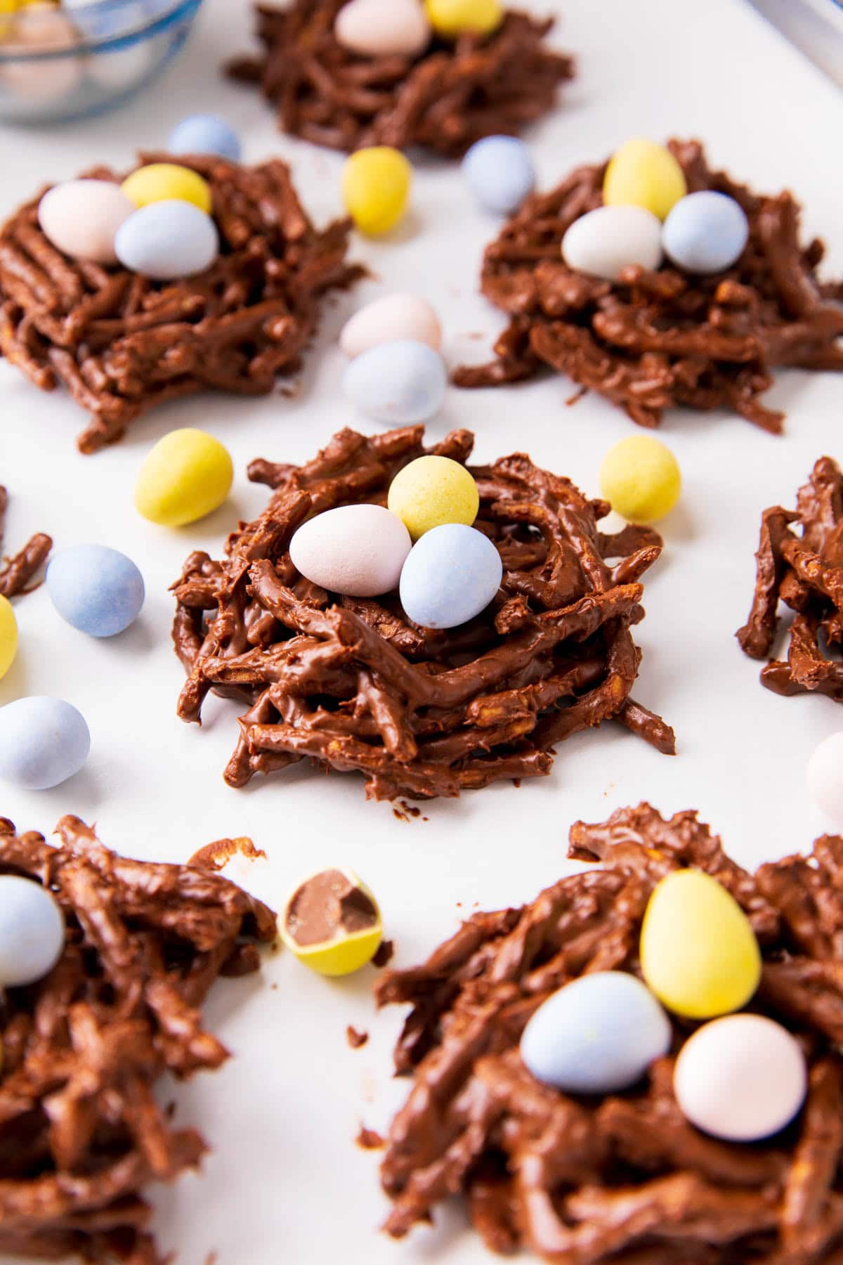 This birds nest recipe for Easter is shown on a lined baking sheet with Easter eggs, chocolate branches and candy.