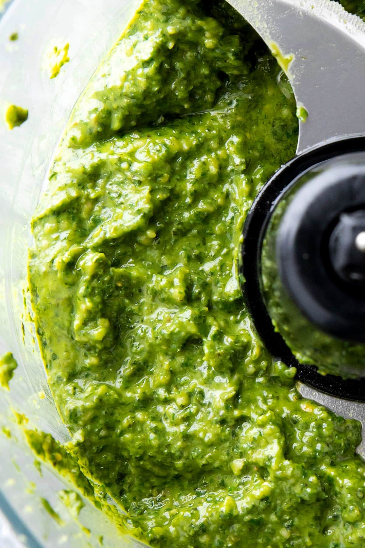 Close up of this easy pesto sauce recipe to show the right texture to know when to stop blending this condiment.
