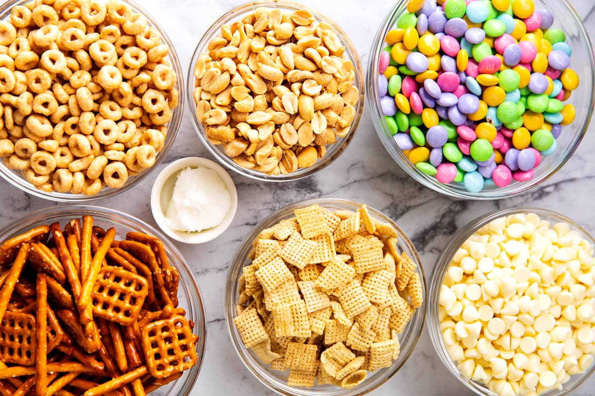 Easter bunny bait snack mix ingredients include Cheerios, white chocolate, coconut oil, peanuts, Easter candies, and Chex mix cereal.