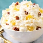 Close up of Pineapple Fluff recipe shows fluffy dessert packed with coconut, old fashioned pineapple and nuts
