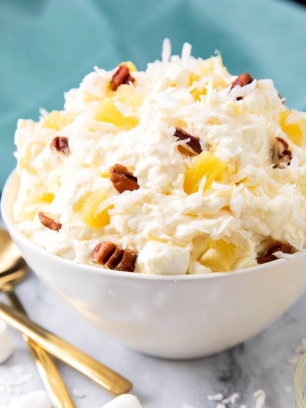 Close up of Pineapple Fluff recipe shows fluffy dessert packed with coconut, old fashioned pineapple and nuts