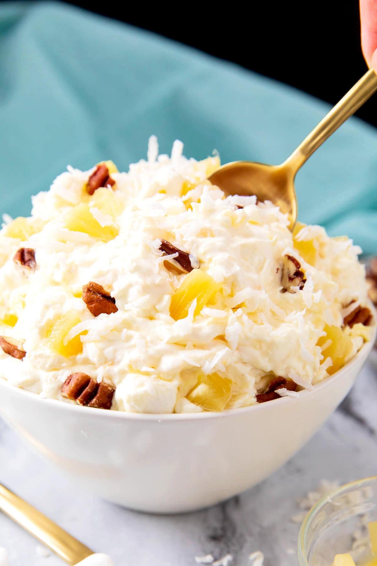 Someone dipping a spoon into a bowl of grandma's old fashioned pineapple fluff.