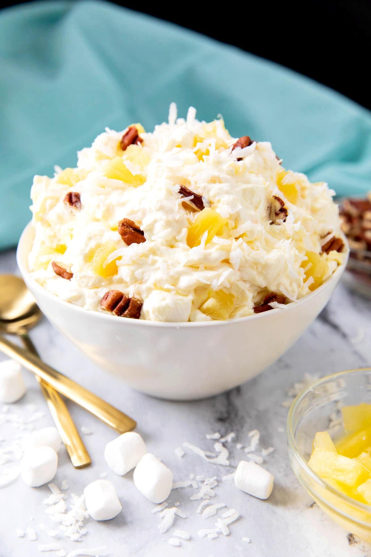 Hawaiian pineapple coconut fluff is served in a dessert bowl topped with pineapple, sweetened coconut, and marshmallows.