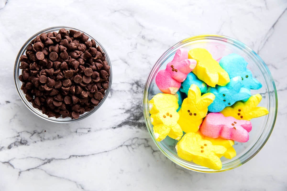 Ingredients for Easter S'mores dip measured in bowls including chocolate chips and Peeps Easter marshmallows.