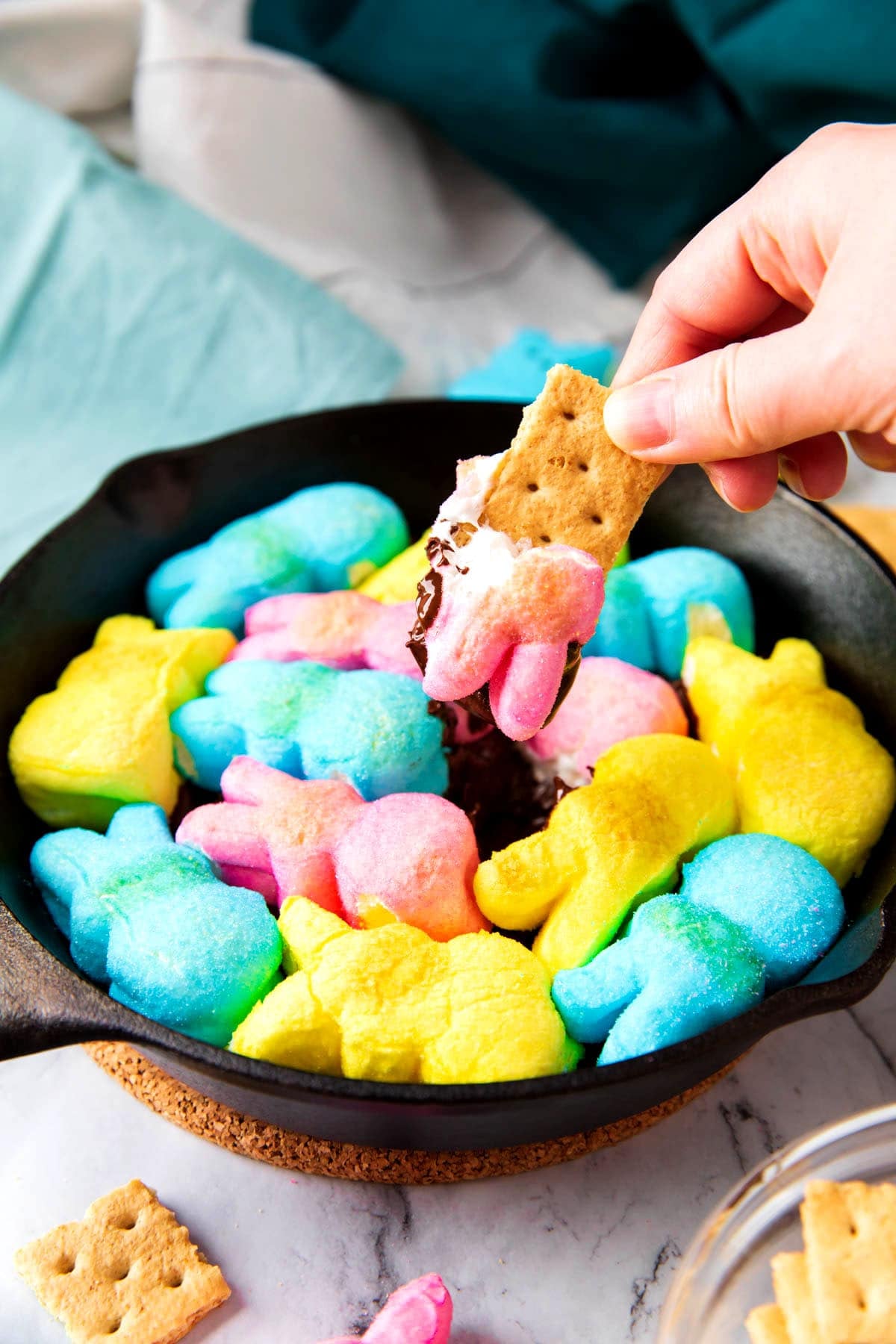 Dipping a graham cracker into a toasted marshmallow Easter bunny in this Peeps s'mores dip.