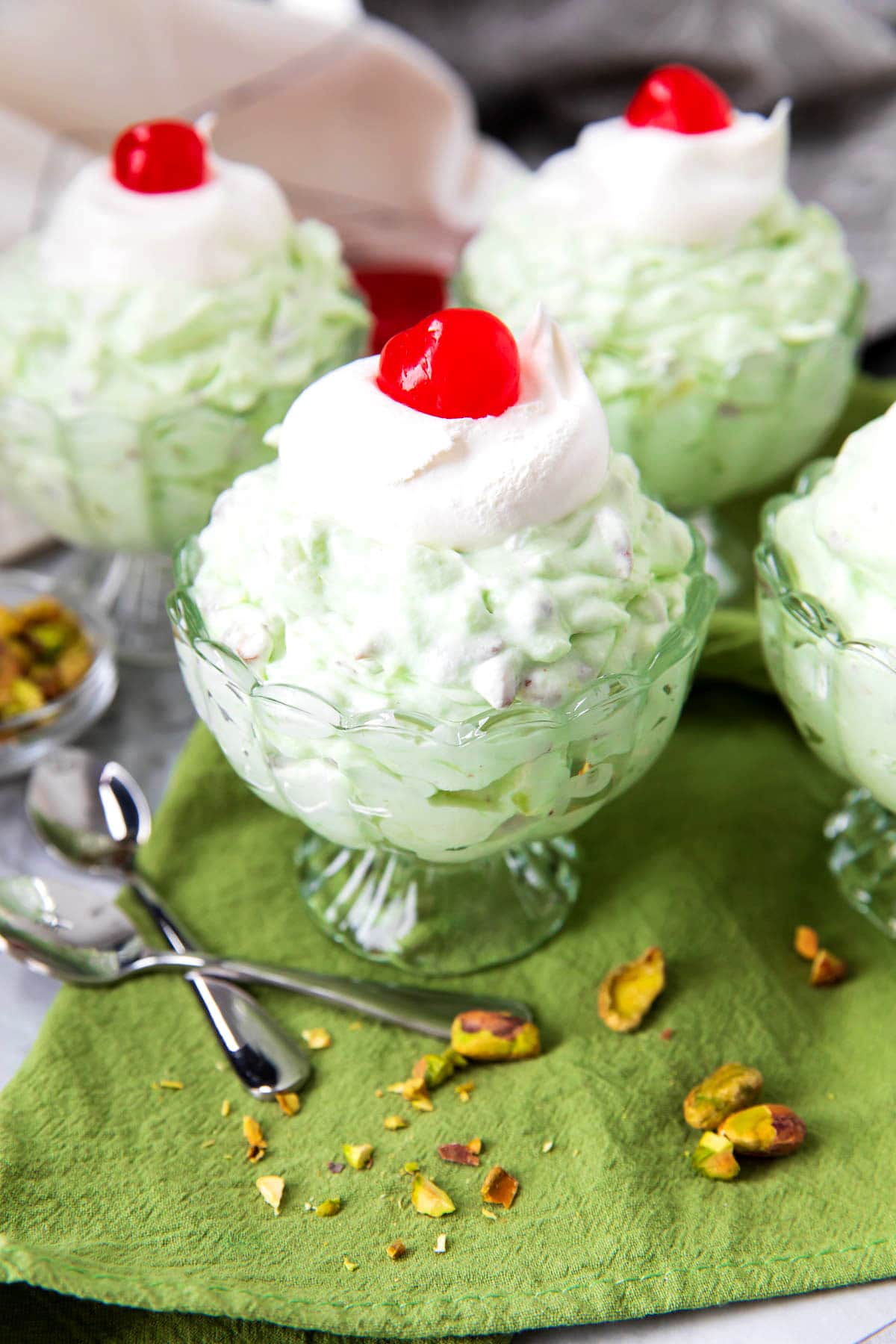 Jello pistachio fluff recipe also known as watergate salad is served in dessert bowls topped with pistachios.