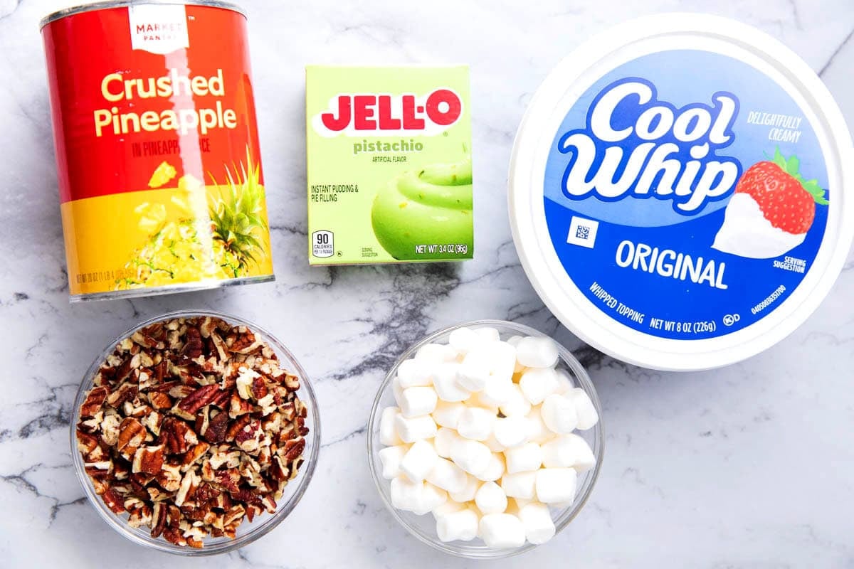 Pistachio fluff dessert ingredients include Jello pistachio instant pudding, crushed pineapples, marshmallows, Cool Whip, and chopped pecans.