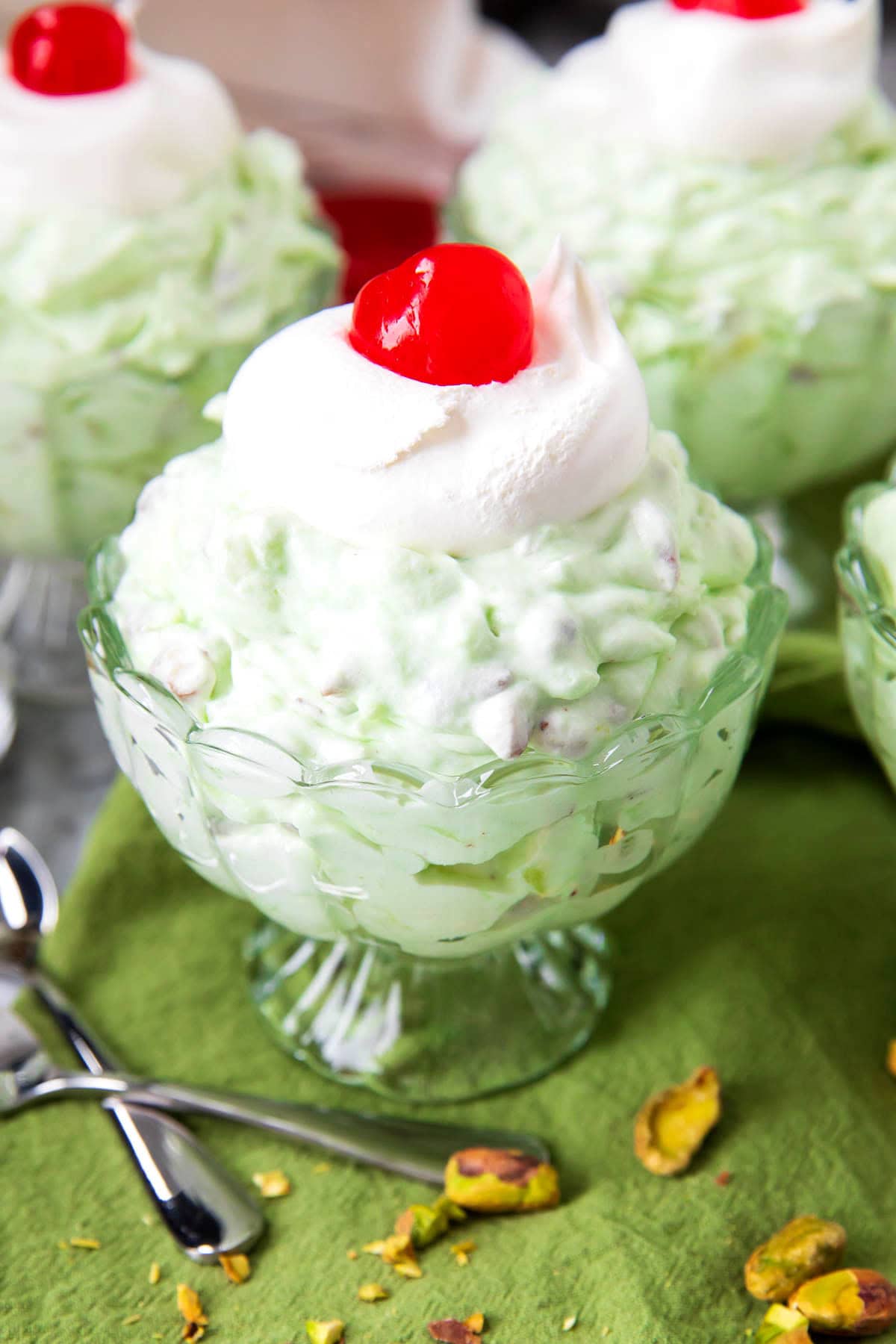Pistachio fluff recipe with pineapple is retro green topped with Cool Whip and served with dessert spoons.