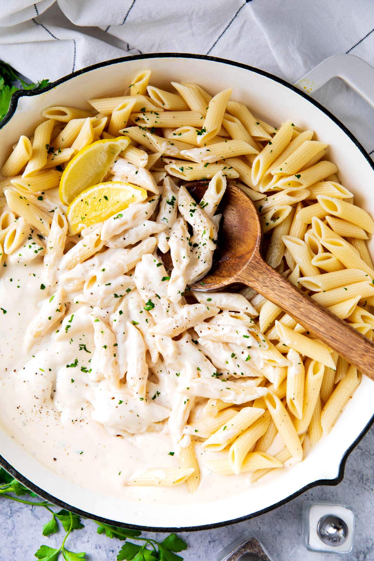 Penne Alfredo pasta is shown with lots of al dente pasta and plenty of Alfredo sauce in a skillet with lemon.