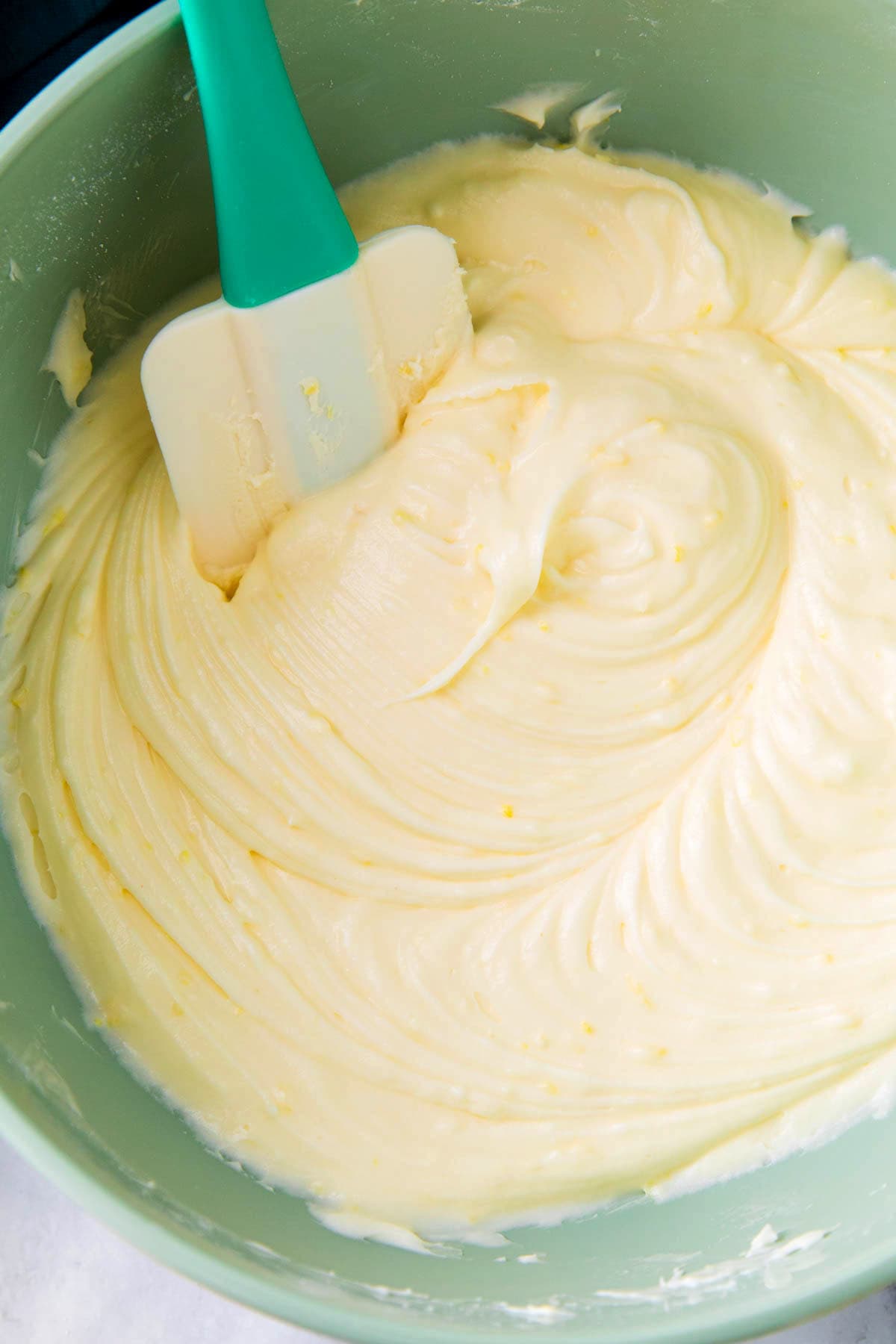 Close up of lemon frosting with cream cheese that's smooth in a mixing bowl.