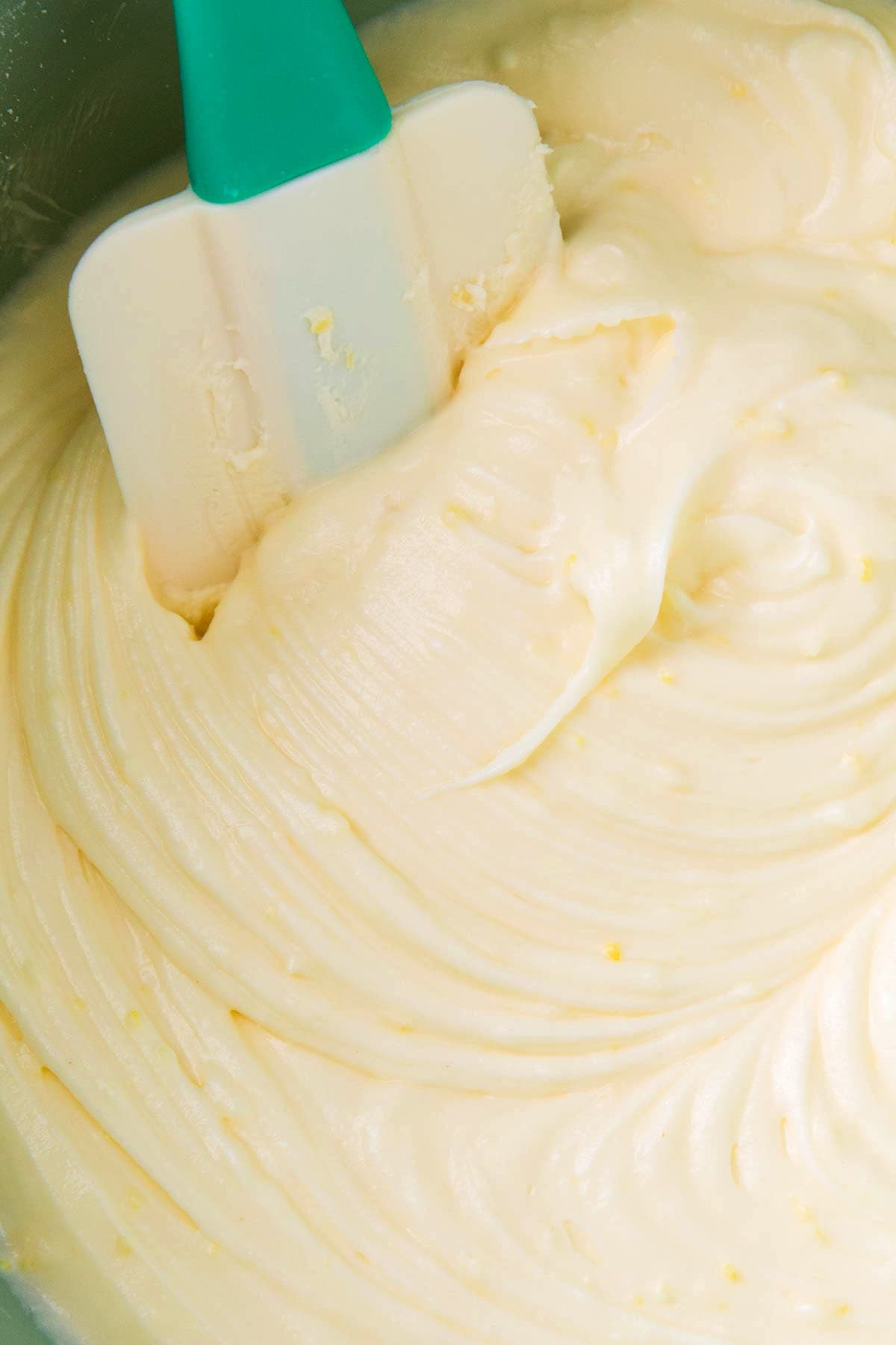 A frosting spatula scooping the best lemon cream cheese frosting made with fresh lemon juice and lemon zest for big lemon flavor.