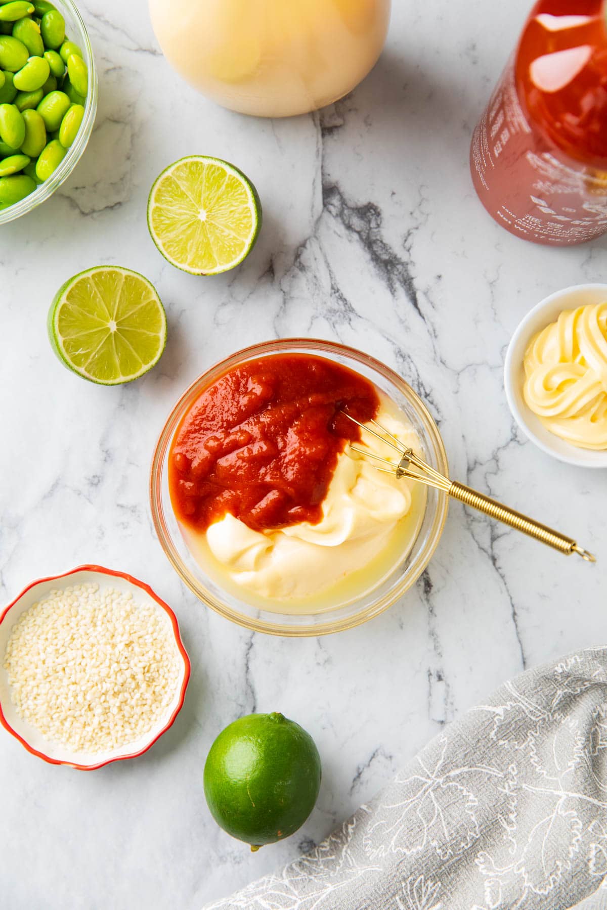 A photo showing How to Make Spicy Mayo Sauce - sriracha, lime juice, and Japanese Kewpie mayonnaise in a mixing bowl.