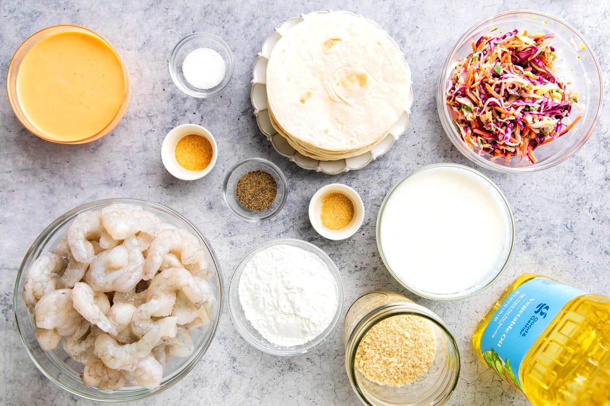 Crispy shrimp taco recipe ingredients include shrimp, spicy mayo, oil, slaw, Panko breadcrumbs, cornstarch, seasonings, and oil for deep frying.
