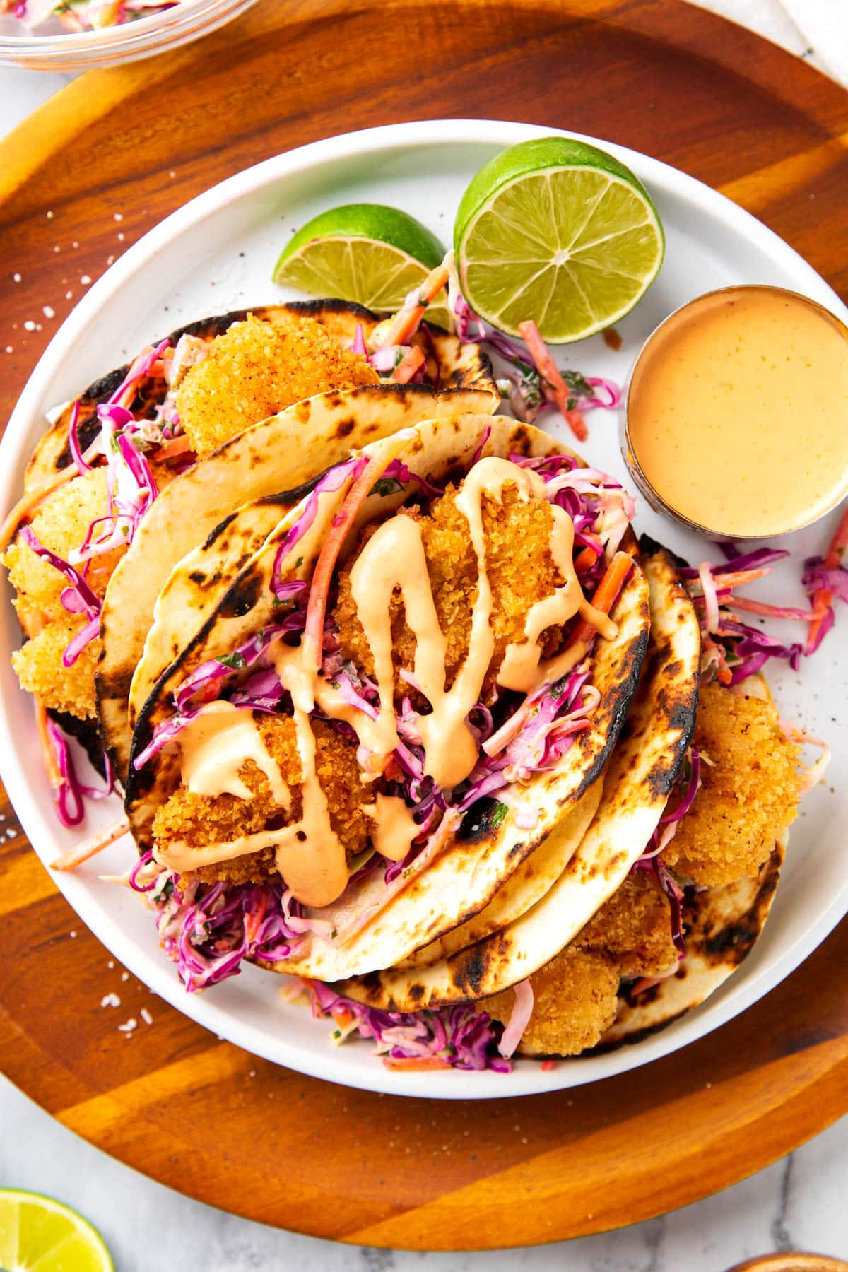Fried shrimp tacos with shredded carrots, red cabbage, cilantro, lime juice, crispy Panko fried shrimp, and spicy creamy sauce