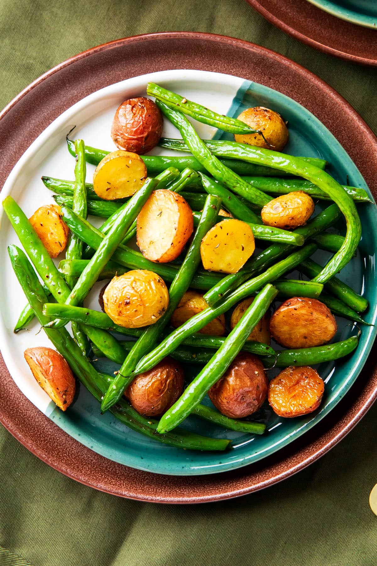Roasted red potatoes and green beans are baked until potatoes are tender on the inside with crisp seasoned exteriors served on a plate.