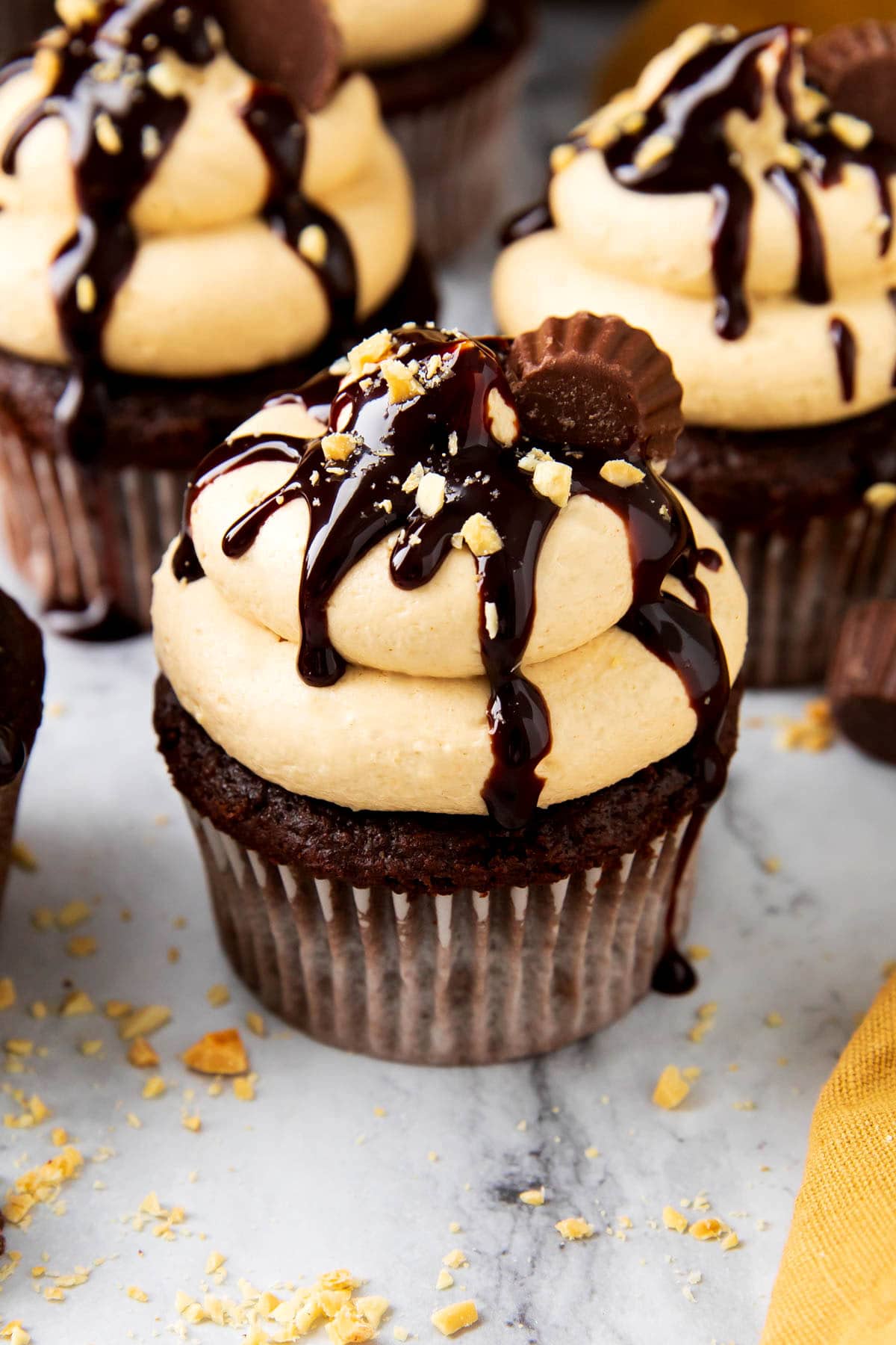 Moist chocolate cupcakes and peanut butter icing with crushed peanuts on top with chocolate drizzle.