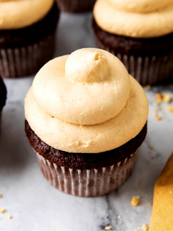 Fluffy, creamy, and smooth peanut butter frosting recipe for chocolate cake is piped onto a cupcake